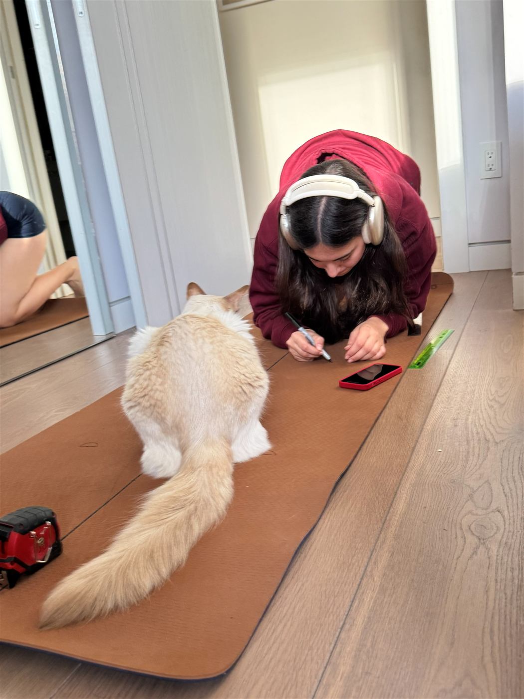 Diana in a plank position on an early hand-marked mat prototype, drawing in her hand placement mark.