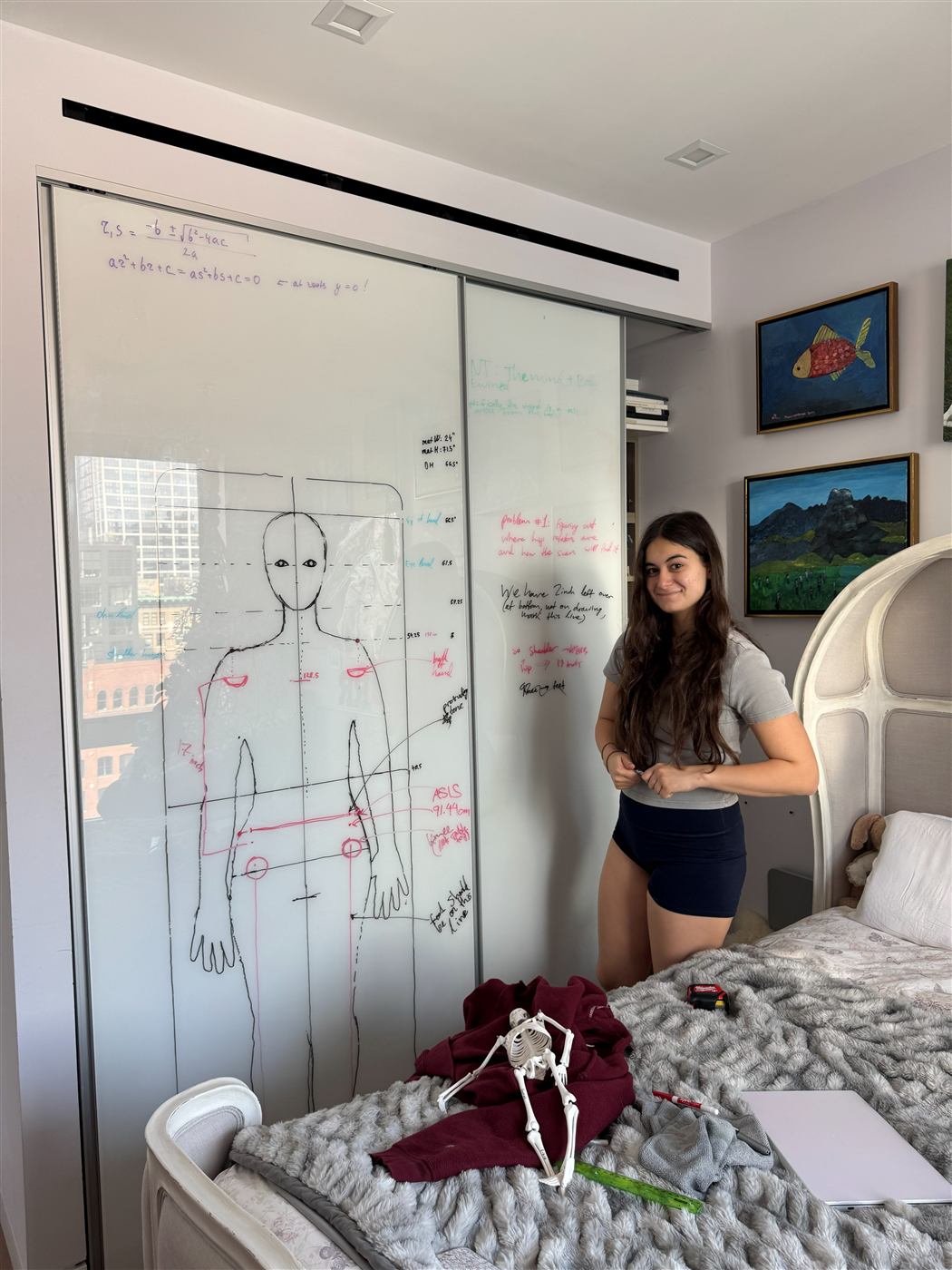Diana standing beside her whiteboard of body-measurement diagrams and geometry calculations used to design the Yo-Mat layout.